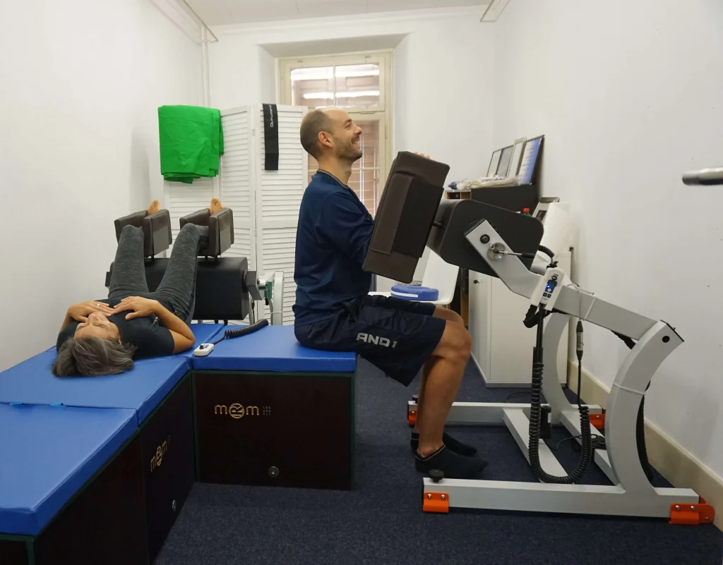 Personas utilizando el equipo MRM en un centro de fisioterapia, que complementa el trabajo de los terapeutas en la preparación y recuperación de atletas y pacientes, sin reemplazar el toque humano profesional.