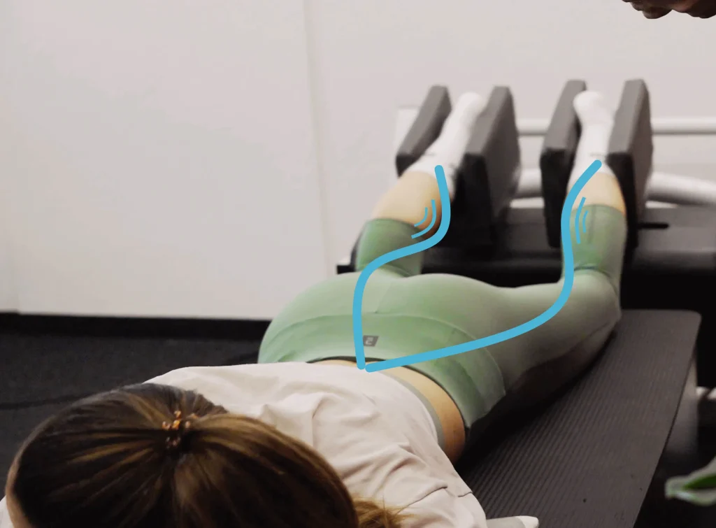 Persona en posición de entrenamiento con piernas sujetas en dispositivo especializado, representando innovación en salud y rendimiento deportivo.